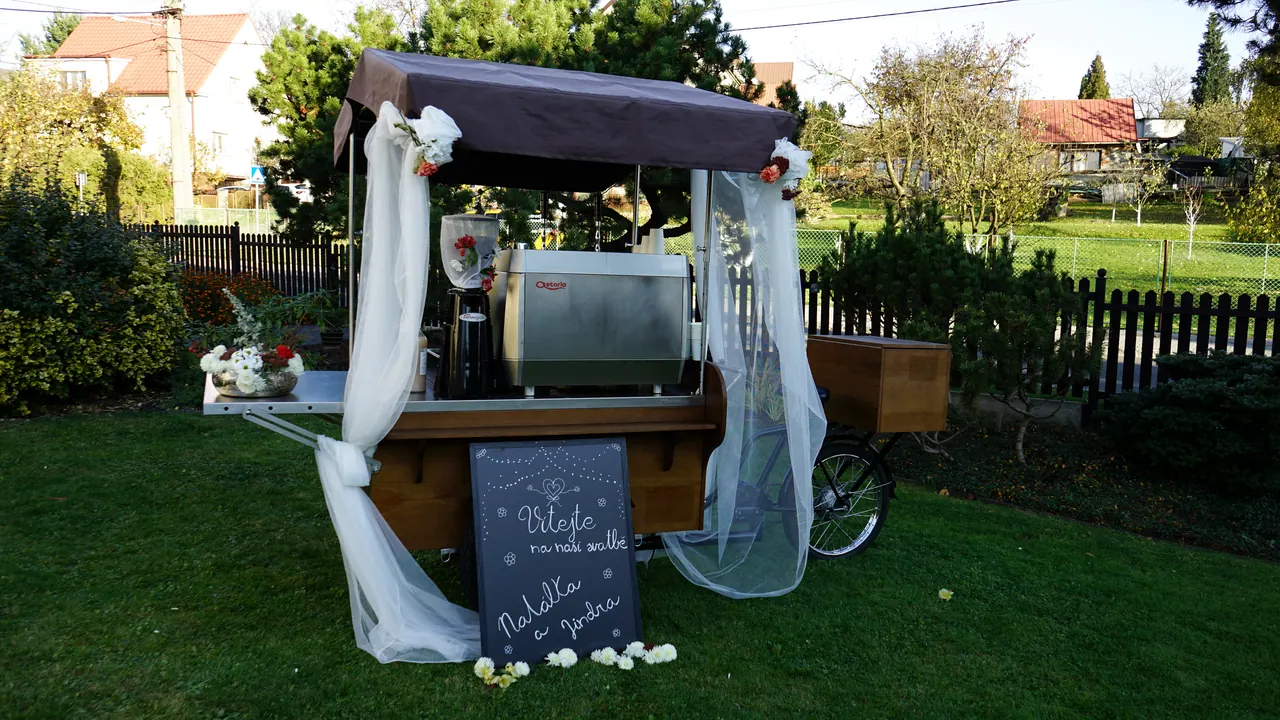 Coffee bike ozdobený tylem a bílými květinami na svatební zahradě